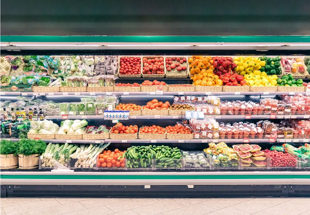 Supermarket produce section with colorful fruits, vegetables.
